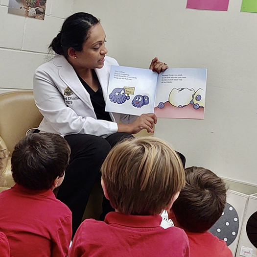 Doctor Dhaliwal reading a picture book to a classroom of children