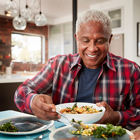 Man placing vegetables onto his dinner plate