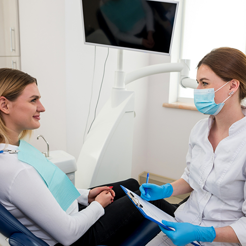 Dental team member with a clipboard talking to a patient