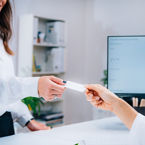 Person handing a card to a dental team member