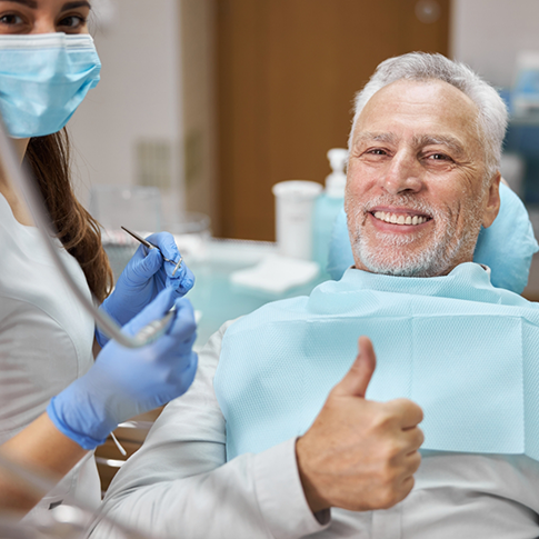 Senior man in the dental chair giving a thumbs up