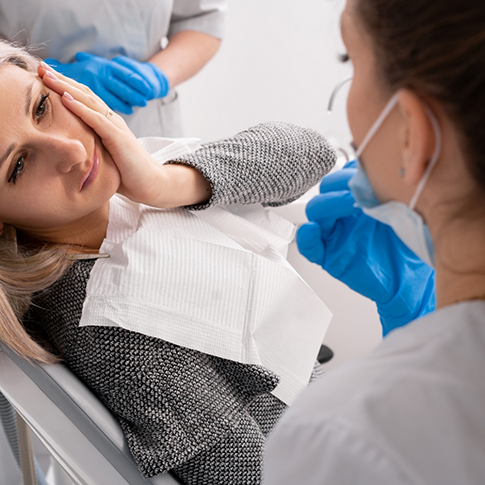 Dental patient holding her cheek in pain
