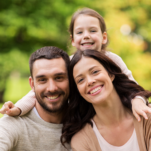Family of three smiling outdoors