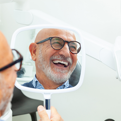 Older man admiring his new smile in a mirror